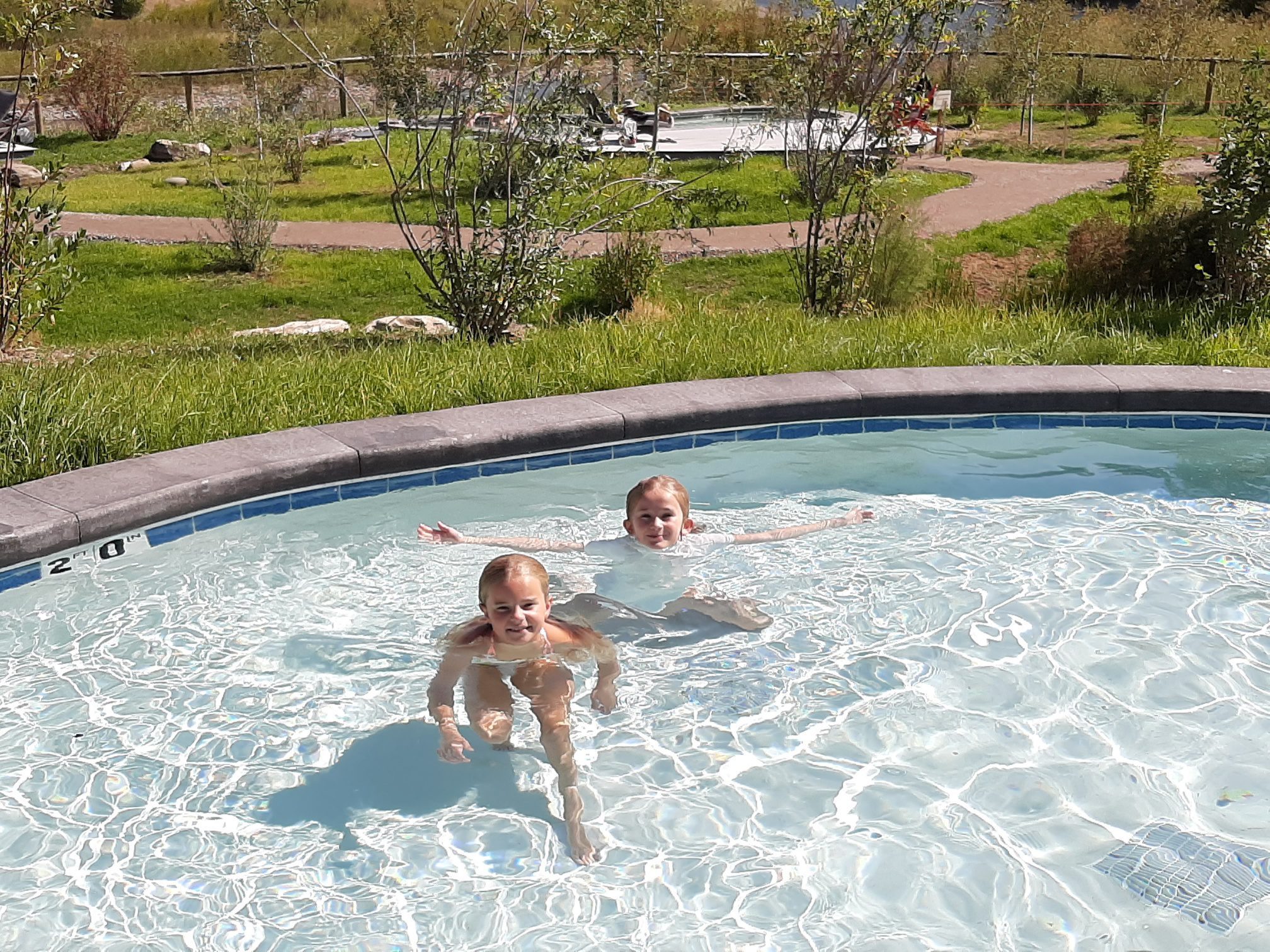 Two blond girls relax in a shallow hot springs pool.