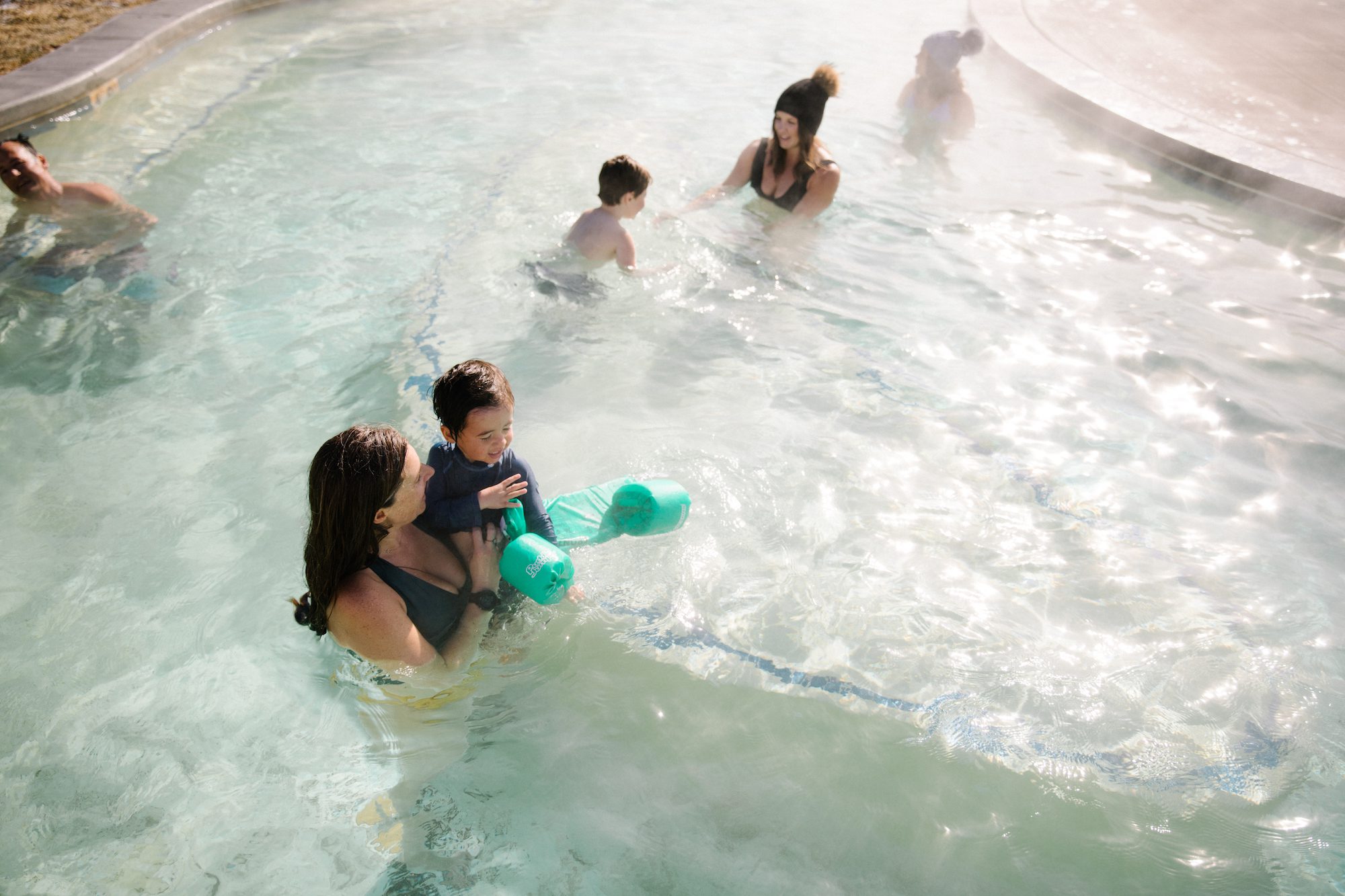 A mother holds her child in a hot springs pool.