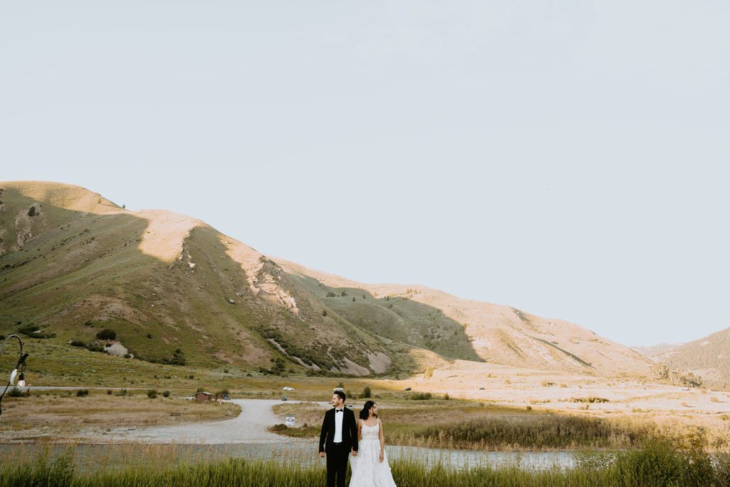 A bride and groom pose in front of the Snake River at Astoria Hot Springs.