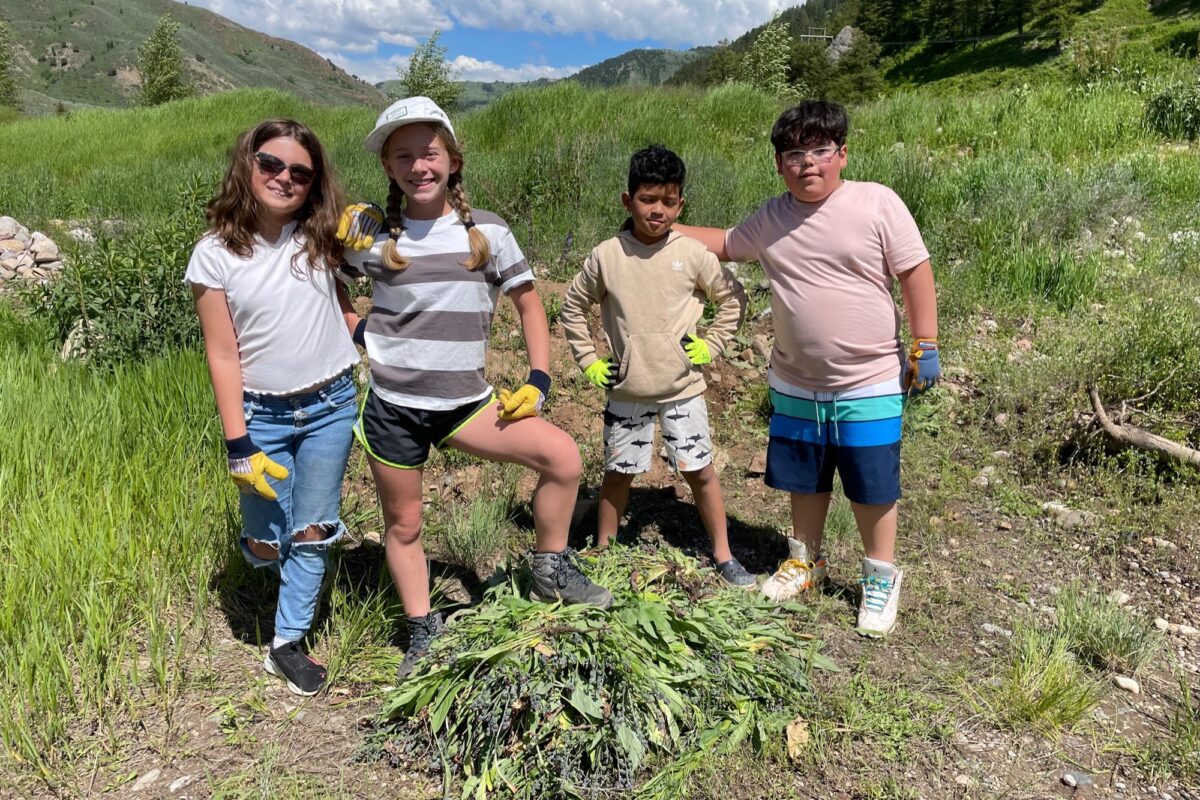 Four young children take a break from pulling weeds.