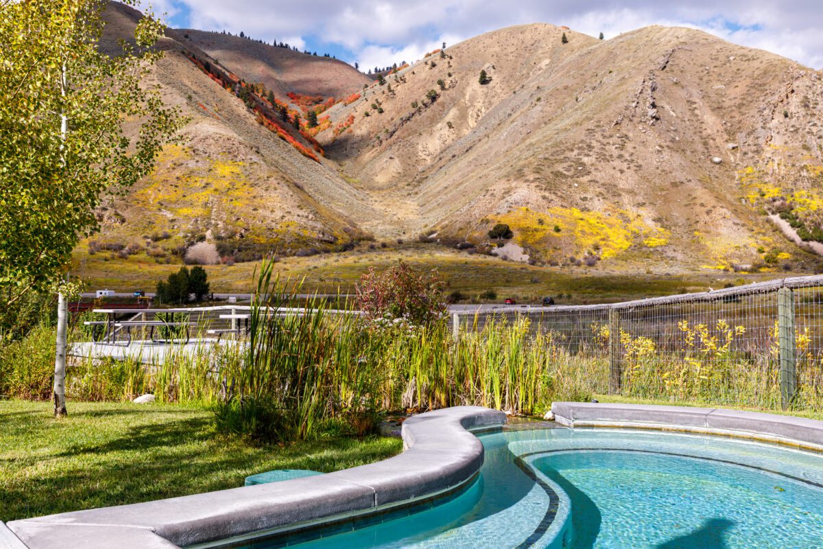 Fall foliage turns yellow and red on the hillside next to an Astoria Hot Springs pool.